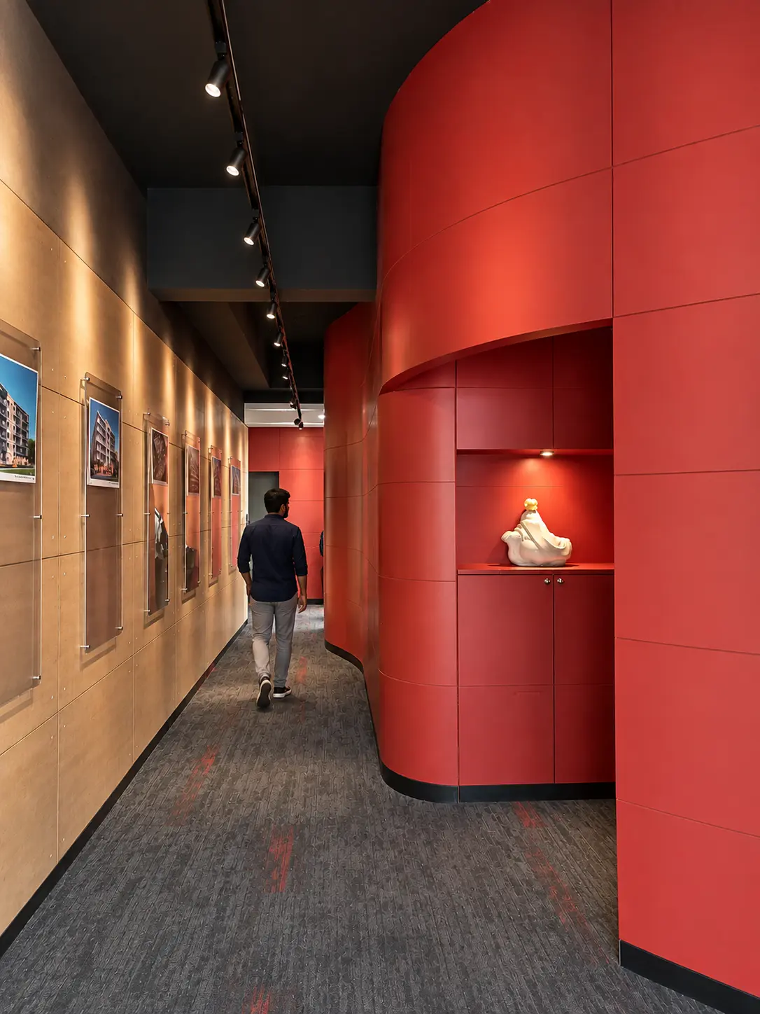 Long office corridor organised by a curved red wall and an opposite gallery display wall