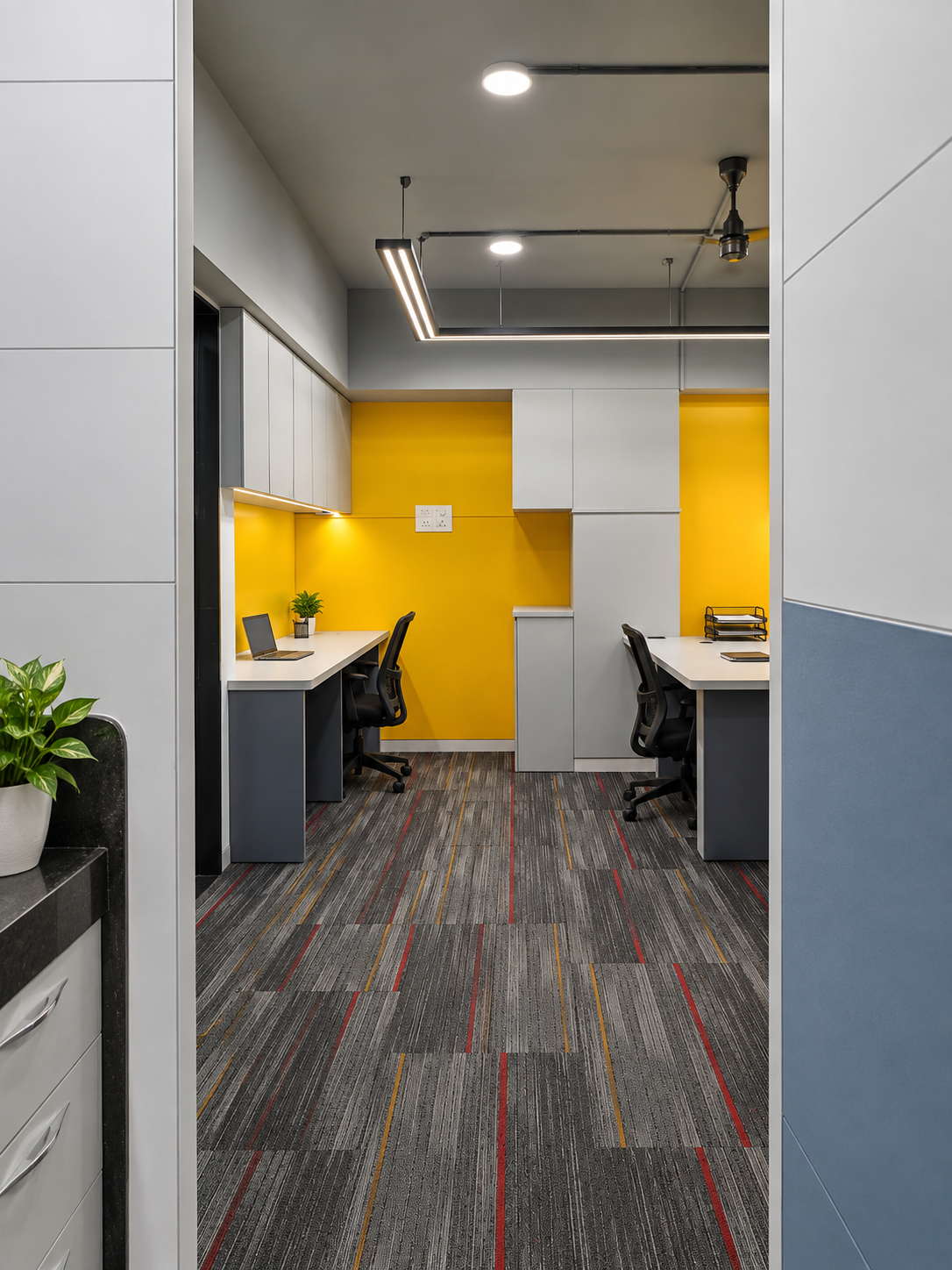 Double workstation nook built into a recessed yellow wall with white and grey cabinetry